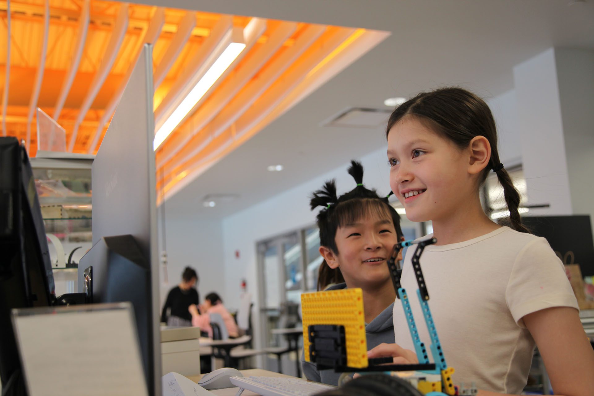 Two students smiling and showing their LEGO engineering project during a collaborative workshop at Valley Robotics Club in Fox Valley.