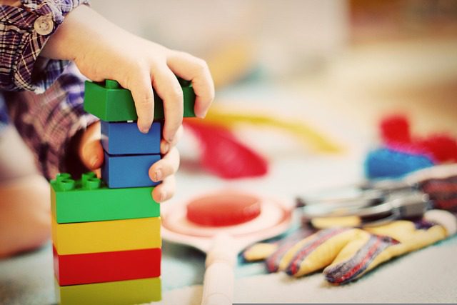 A child's hands stacking colorful LEGO Duplo bricks to develop fine motor skills during a creative play session.