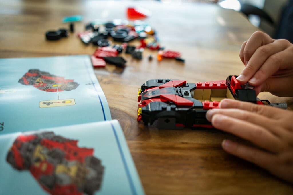 A student following step-by-step instructions to build a LEGO race car.