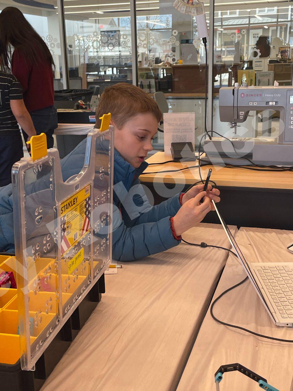 A focused student working on a project next to a sewing machine during a 2025 Fall Program class at Valley Robotics Club.