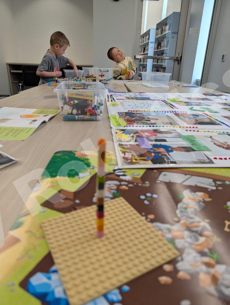 Two students focusing on their Lego model projects across a table in a well-stocked classroom during a 2025 Fall Program class.